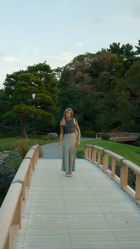 Maria walking along a white elevated walkway in Tokyo