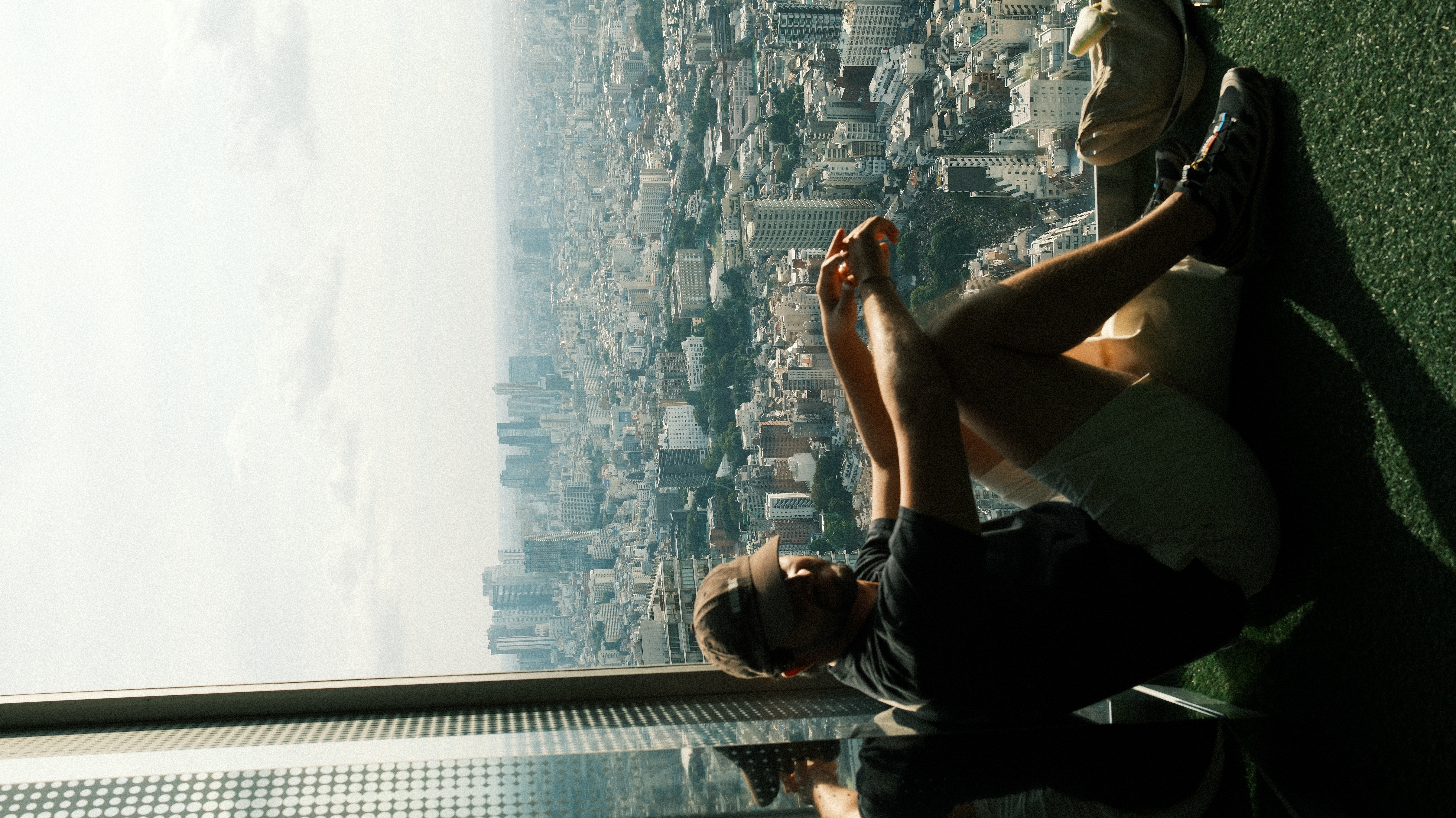 Zé lying on Shibuya Sky observation deck looking out over Tokyo